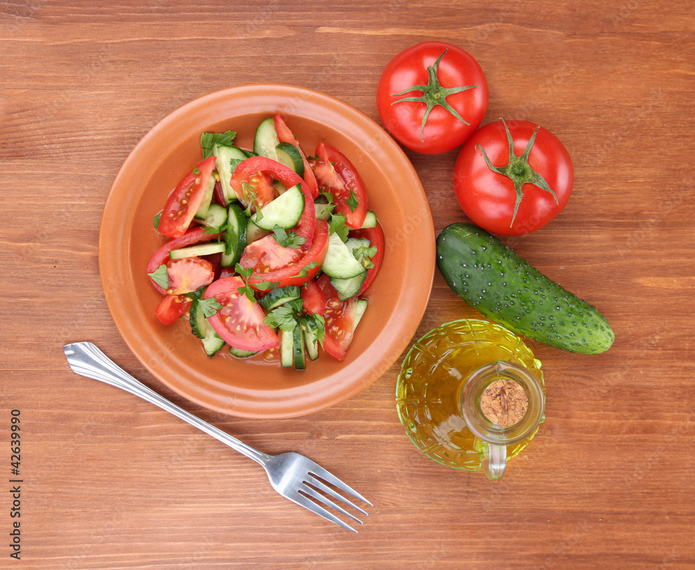 Fresh salad with tomatoes and cucumbers on wooden background