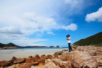 Portrait of a young man standing on a beach with a camera