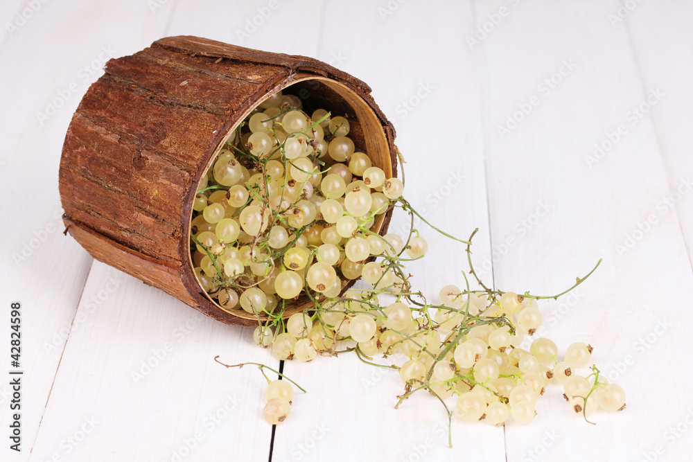 White currants in wooden cup on wooden background