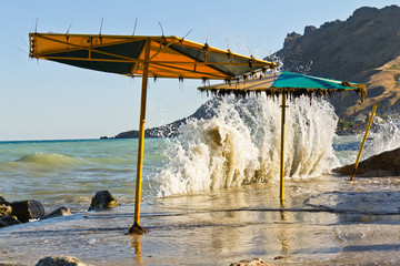 The waves break on the waterfront with beach umbrellas