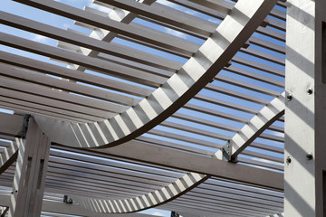 White Wooden Arbor/Pergola with blue sky in distance.