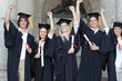 © WavebreakmediaMicro - Smiling graduates posing while raising arms