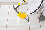 Fototapeta  - Worker with hammer removes old white tiles from floor
