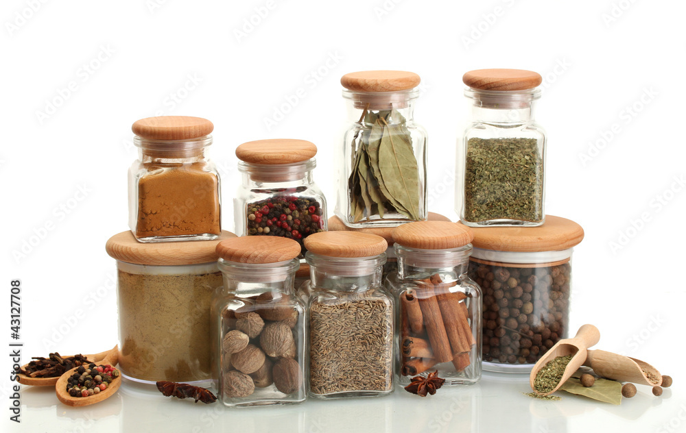 jars and wooden spoons with spices isolated on white