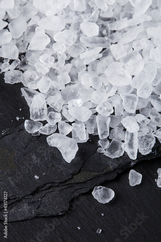 Naklejka na szybę Coarse sea salt on black slate stone background, closeup