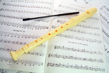 Block-flutes Placed Over Textbook With Musical Notes.