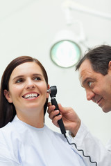 Wall Mural - Doctor using an otoscope to look at the ear of a patient