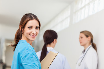 Wall Mural - Smiling nurse  while standing in a hallway with a patient and a