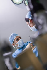 Wall Mural - Serious doctor giving a surgical scissor to a nurse