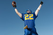© Pete Saloutos/Blend Images - Caucasian football player holding football with arms raised