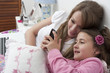 © GM Visuals/Blend Images - Hispanic mother and daughter looking at cell phone