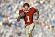 © Pete Saloutos/Blend Images - African American football player running on field in game