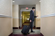 © Ming H2 Wu/Blend Images - Asian businessman pulling suitcase in hotel
