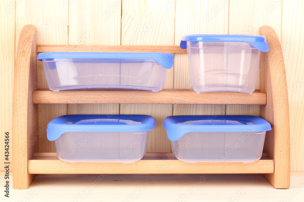 Plastic containers for food on shelf on wooden background