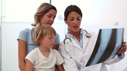 Wall Mural - Doctor examining the X-ray next to a mother and her child