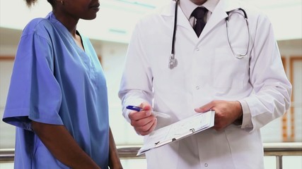 Wall Mural - Doctor holding a clipboard next to a nurse