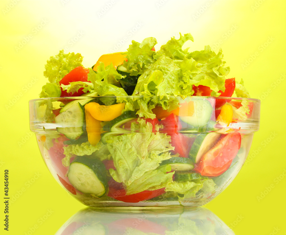 fresh vegetable salad in transparent bowl on green background