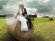 Bride and groom sitting on hay bales