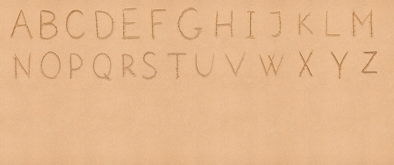 Handwriting English alphabet on flat sand with empty space appro