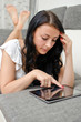 © M-Production - Brunette girl with tablet pc on the sofa.