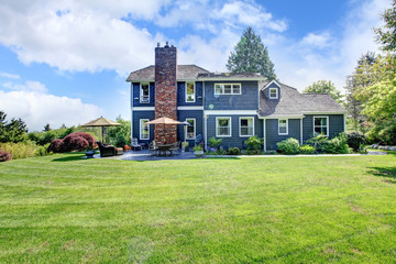 Large blue house with grass and chimney.