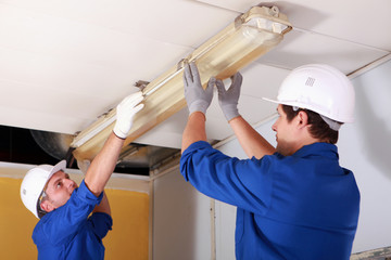 Two electrician repairing office lighting