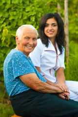 Smiling elderly woman outdoors with doctor / nurse