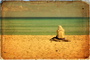 Wall Mural - Woman sitting on sand seen from behind