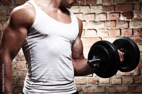 Fototapeta na wymiar Muscular guy doing exercises with dumbbell