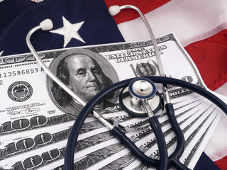 100 dollar bills and stethoscope over american flag