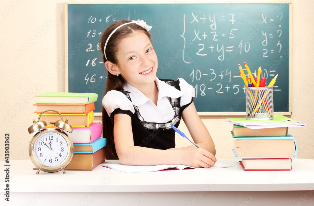 little schoolchild in classroom write in notebook