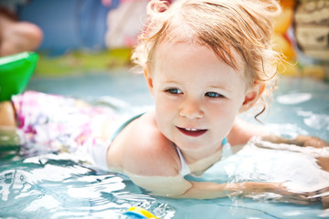 Little blondie girl in the swimming pool, soft focus