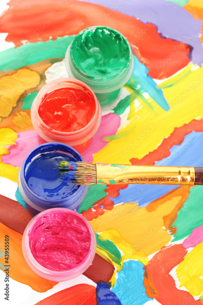 Jars with colorful gouache on a bright picture close-up