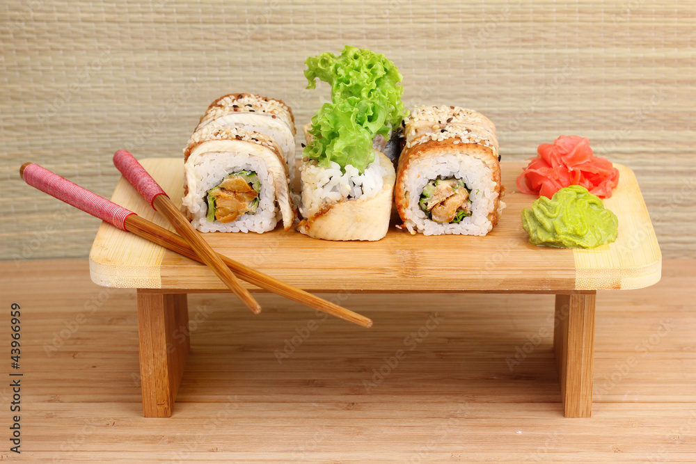 Tasty rolls served on wooden plate on wooden background
