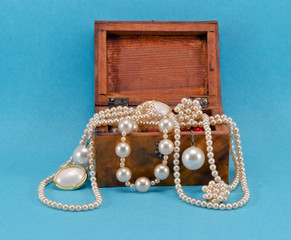 Pearl jewelry in retro wooden box on blue