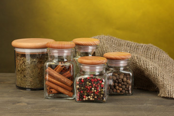 Wall Mural - jars with spices on wooden table on yellow background