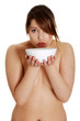 © Piotr Marcinski - Naked woman is drinking from white bowl.