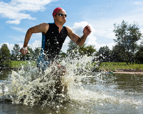 Fototapeta na wymiar Triathlet rennt aus dem Wasser