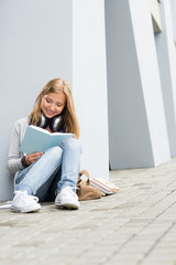 Wall Mural - Smiling young study woman read book outdoor