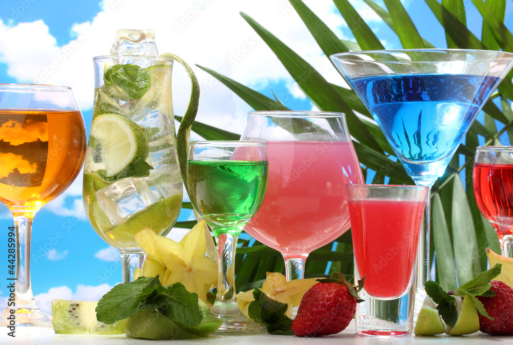 Glasses of cocktails on table on blue sky background