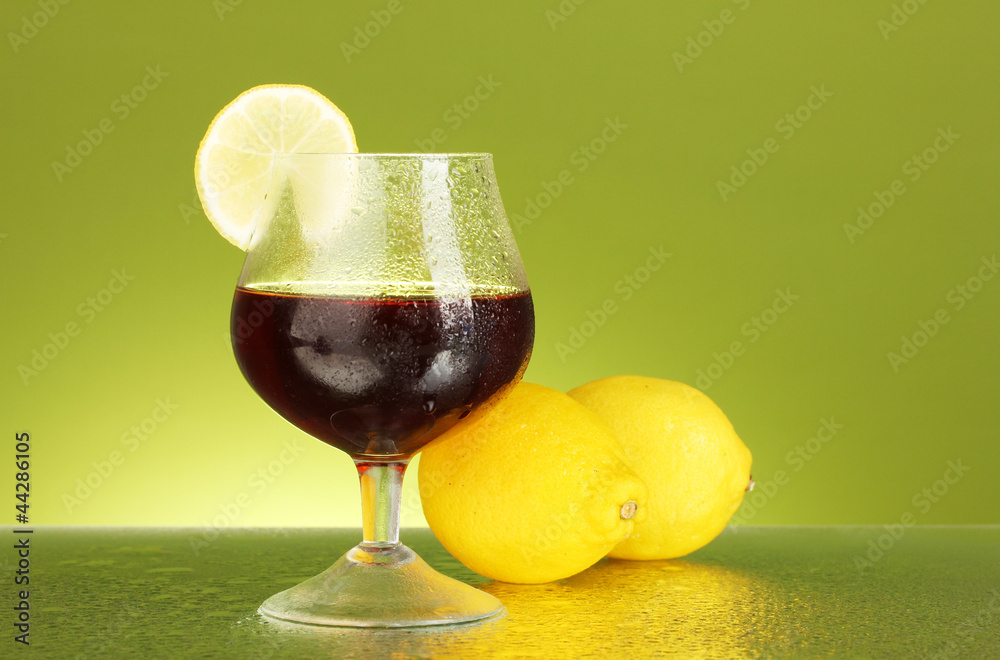 glass of brandy on green background close-up