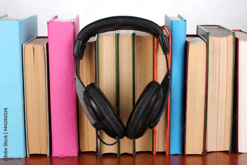 Headphones on books on wooden table on white background