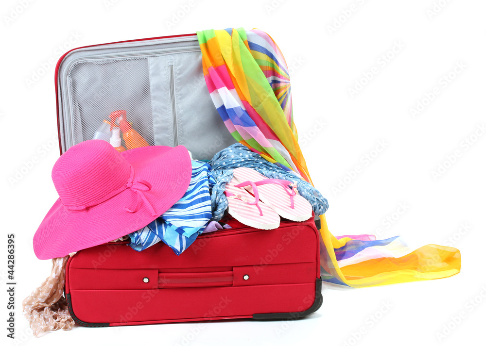 Suitcase with summer clothes, a hat and suntan isolated on