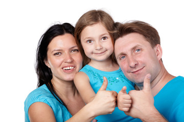 Family of three in blue shirts gives their thumbs up.