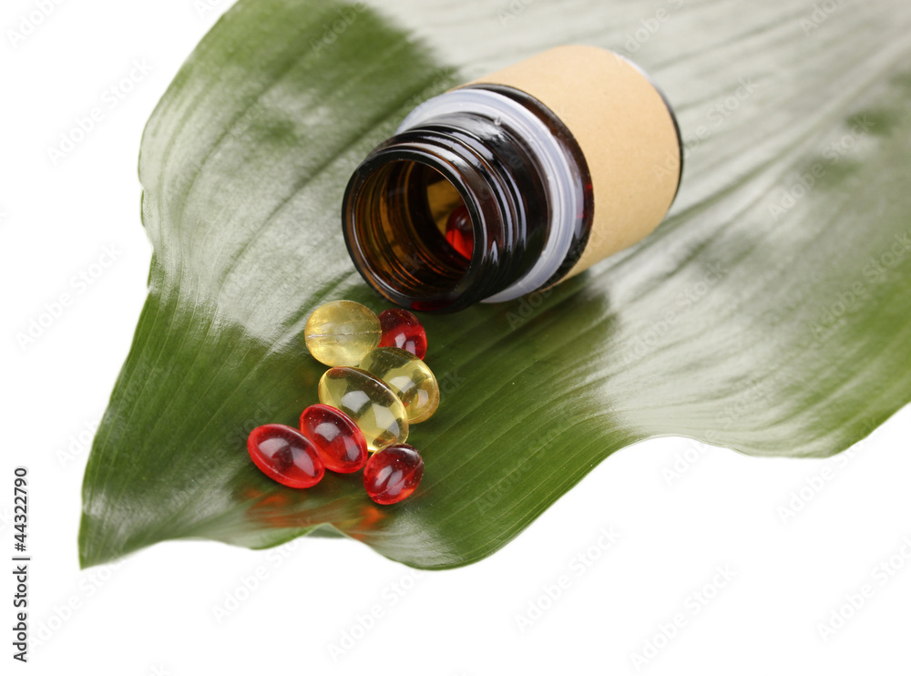 tablets on green leaf with bottle isolated on white