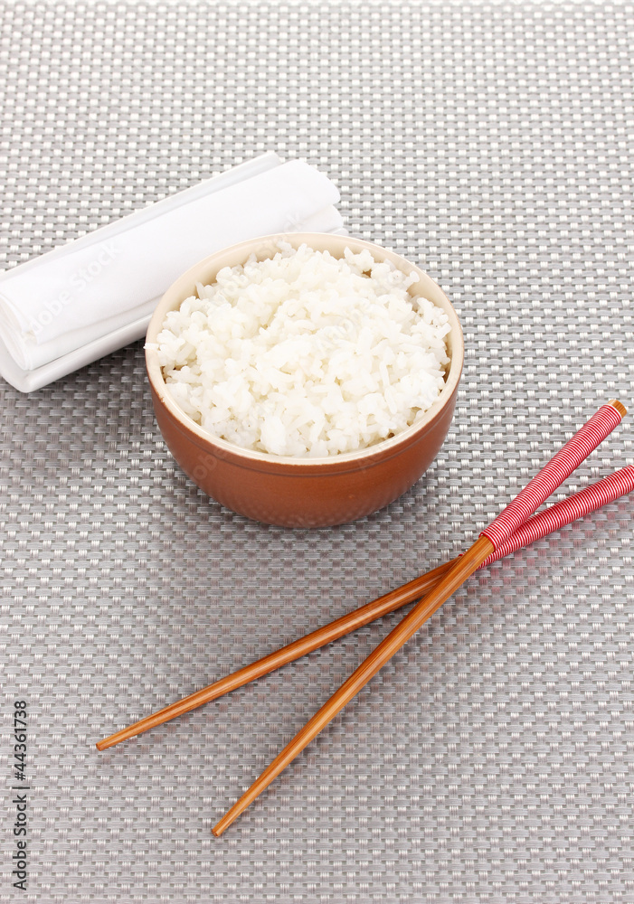 Bowl of rice and chopsticks on grey mat