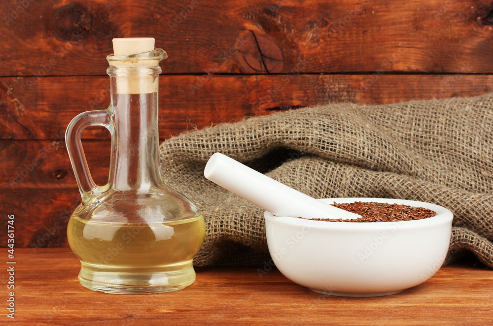 Mortar with flax seeds on wooden background close-up