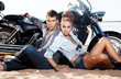 Extreme couple sitting by motorcycle. Adventure and travel