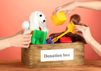 Donation box with children toys on red background close-up