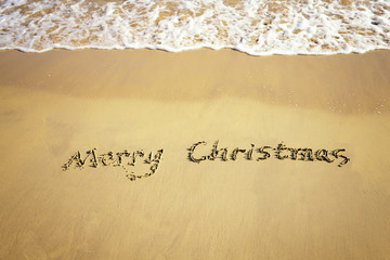 Wall Mural - Merry Christmas handwritten in sand on beach